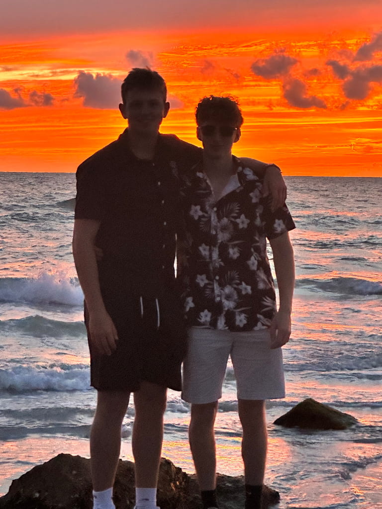 Two business partners standing together on a beach at sunset representing friendship and partnership