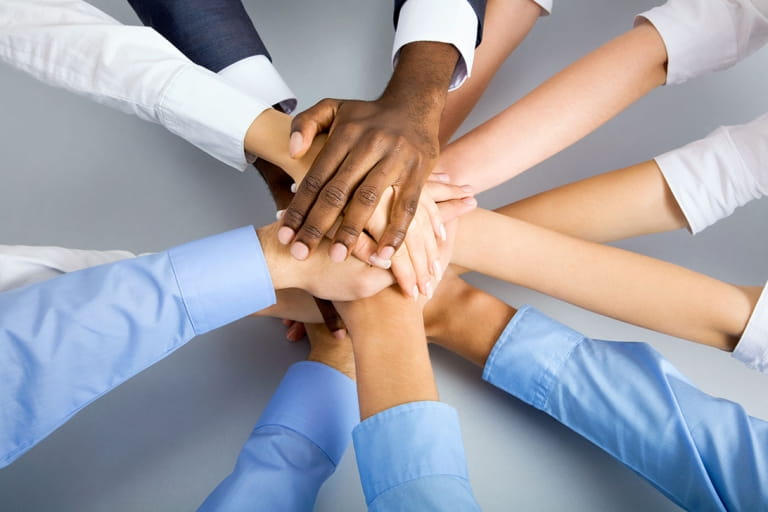 Diverse team members stacking hands together to represent teamwork, collaboration, and shared business goals